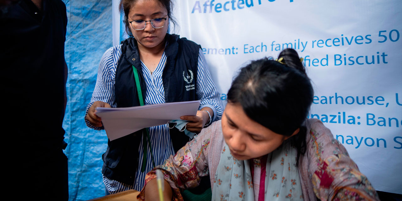 Photo showing WFP staff checking off names for the distribution of fortified biscuits in the immediate aftermath of devastating flash floods in Chittagong, Bangladesh, in August 2023.