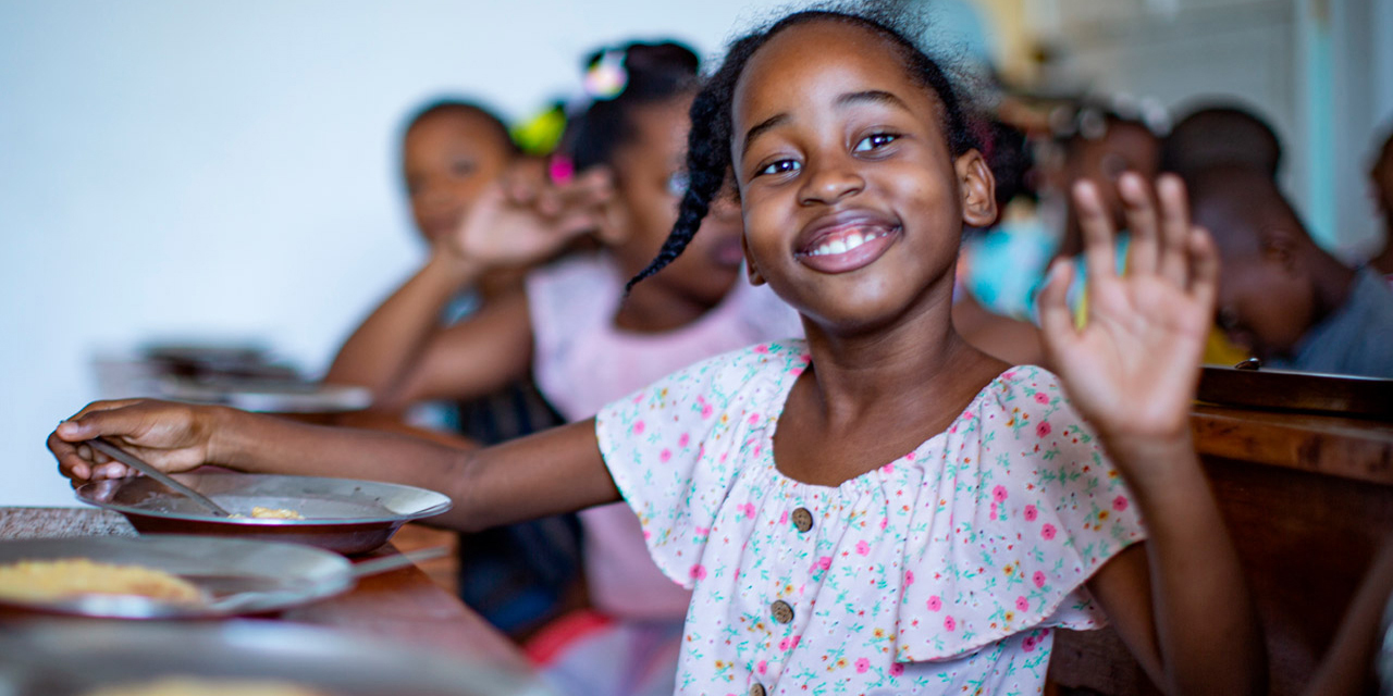 Photo showing a girl enjoying her WFP school meal in Grand'Anse province, Haiti.