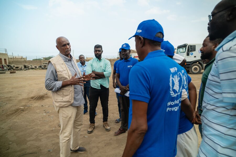 A man in a khaki WFP jacket addressed a small group of WFP drivers in blue shirts